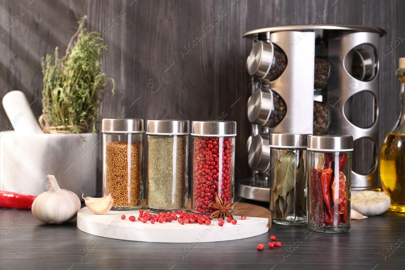 Different spices and glass jars on grey wooden table Photo of Different spices and glass jars on grey wooden table