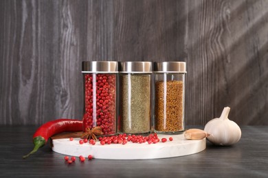 Photo of Different spices and glass jars on grey wooden table
