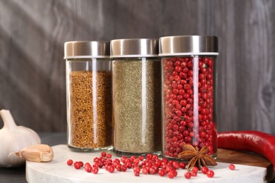 Photo of Different spices and glass jars on grey wooden table, closeup