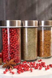 Photo of Different spices and glass jars on board, closeup
