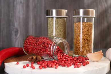 Photo of Different spices and glass jars on table, closeup