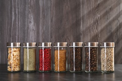 Photo of Different spices in glass jars on grey wooden table