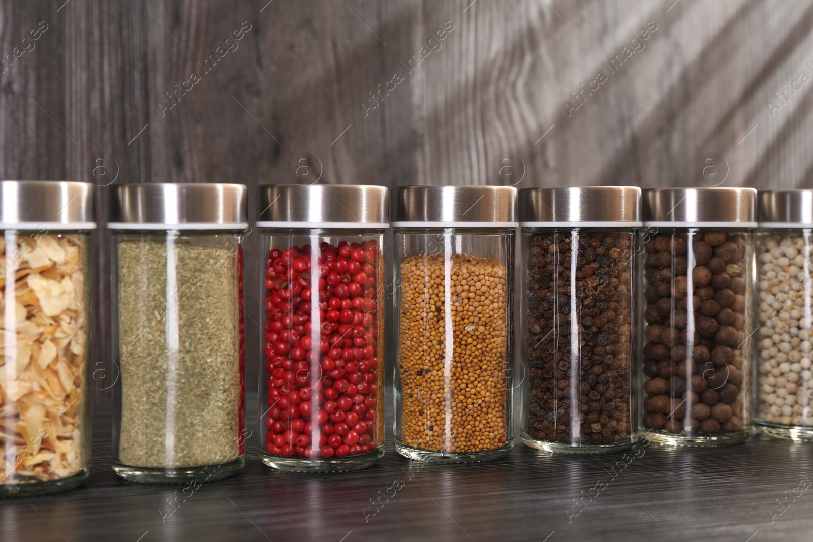 Different spices in glass jars on grey wooden table, closeup Photo of Different spices in glass jars on grey wooden table, closeup