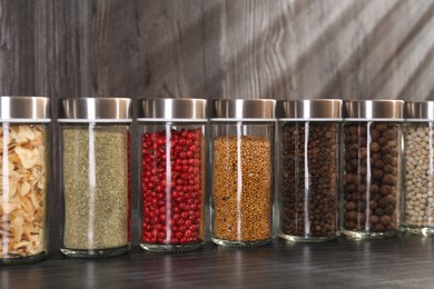 Photo of Different spices in glass jars on grey wooden table, closeup