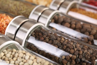 Photo of Different spices in glass jars as background, closeup