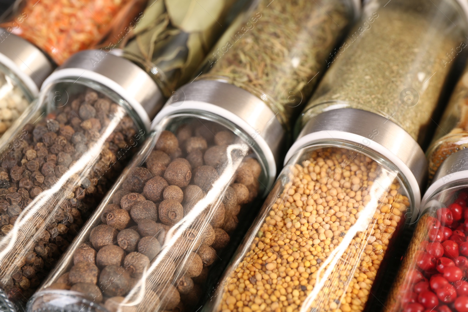 Different spices in glass jars as background, closeup Photo of Different spices in glass jars as background, closeup