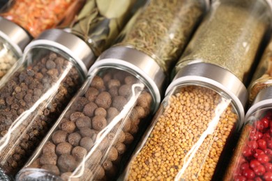 Photo of Different spices in glass jars as background, closeup