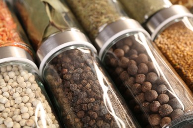Photo of Different spices in glass jars as background, closeup