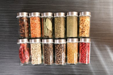Photo of Different spices in glass jars on grey wooden table