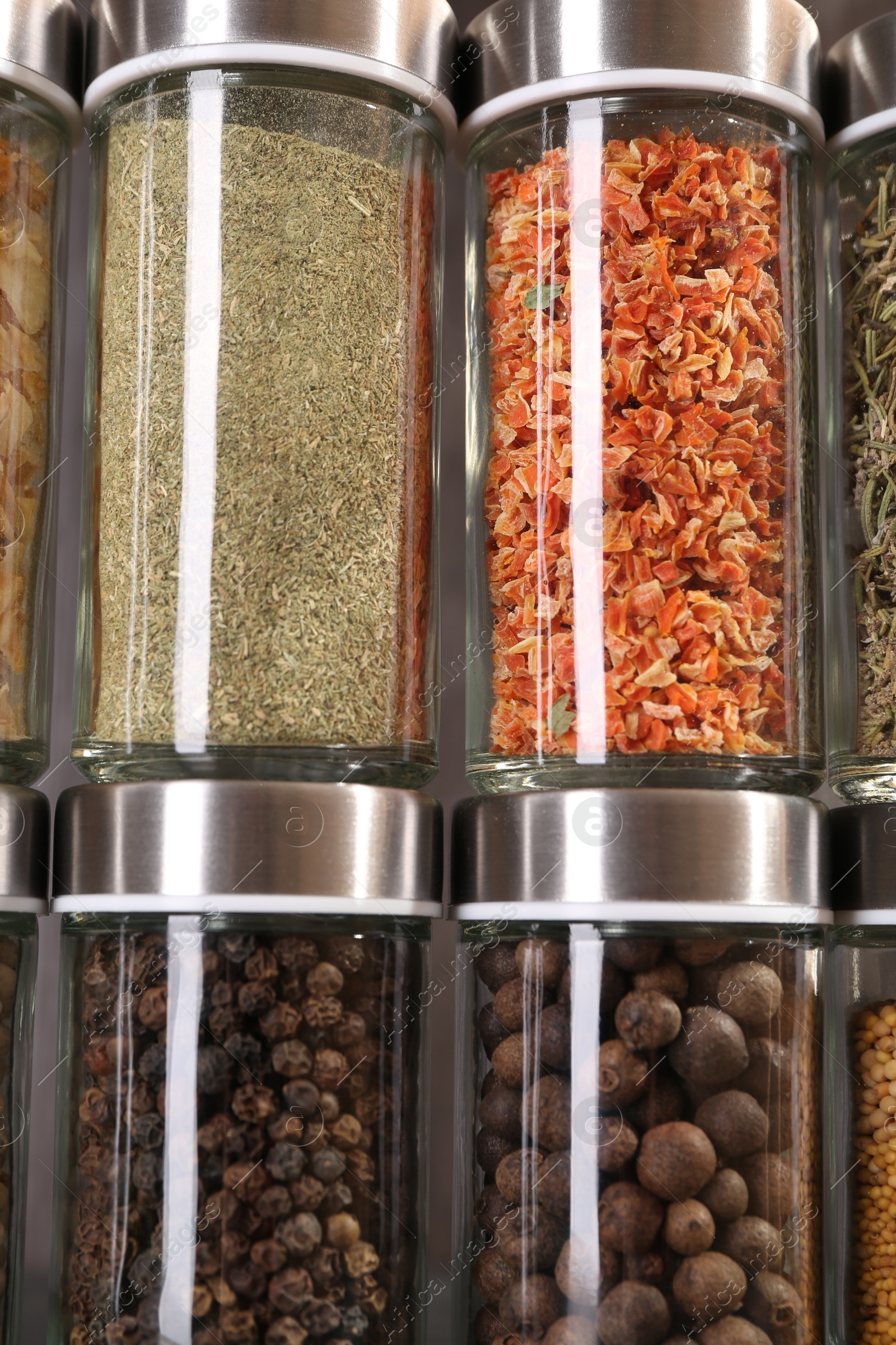 Different spices in glass jars against grey background, closeup Photo of Different spices in glass jars against grey background, closeup
