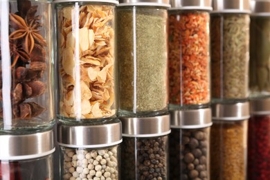 Photo of Different spices in glass jars as background, closeup