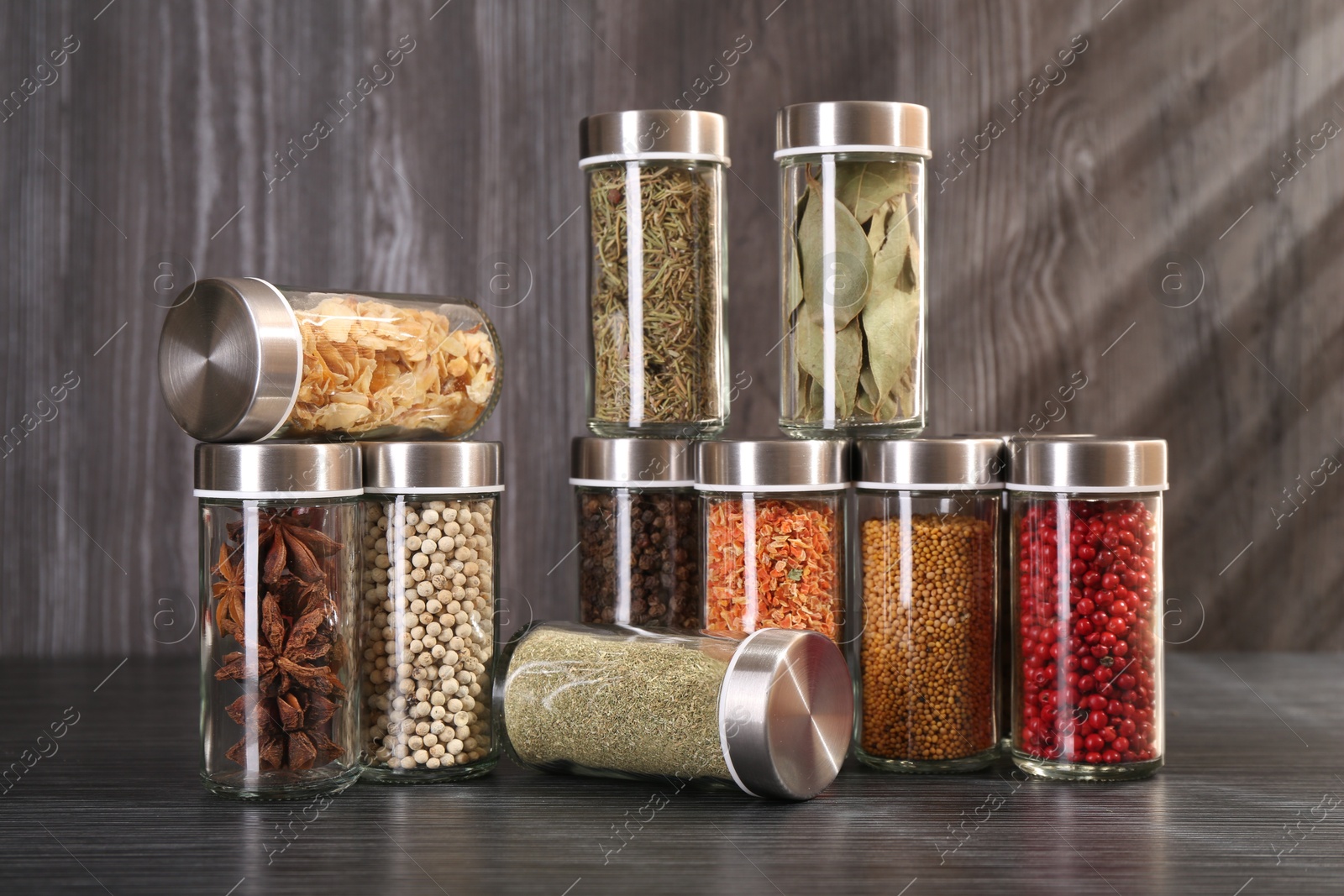 Photo of Different spices in glass jars on grey wooden table