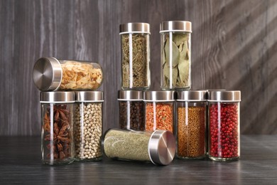 Photo of Different spices in glass jars on grey wooden table