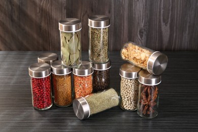 Photo of Different spices in glass jars on grey wooden table