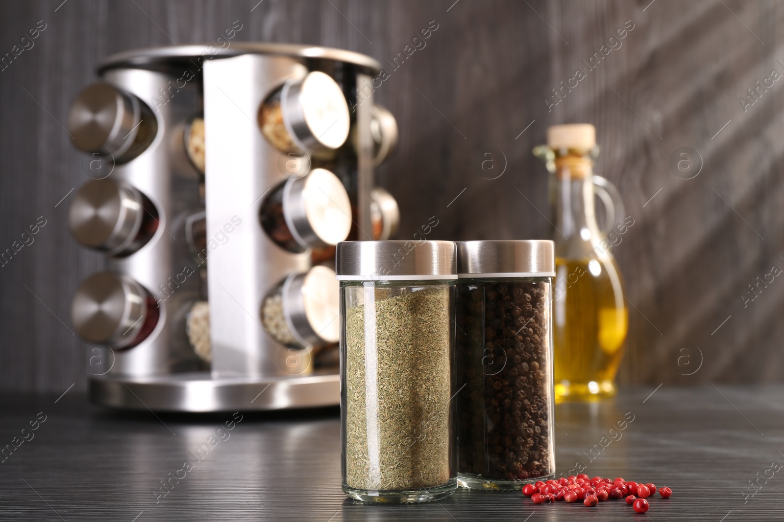 Photo of Different spices in glass jars on grey wooden table, closeup