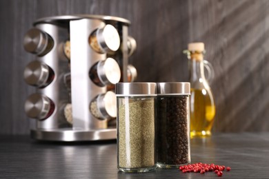 Photo of Different spices in glass jars on grey wooden table, closeup