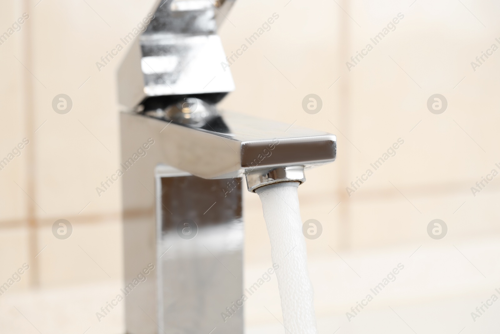 Photo of Water saving concept. Stream of water flowing from tap indoors, closeup