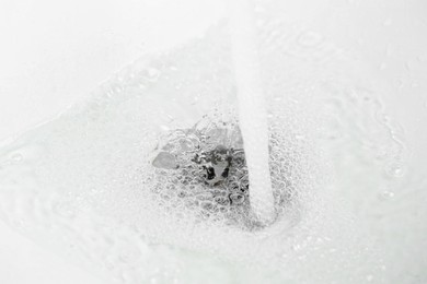 Photo of Water saving concept. Water going into sink drain, closeup