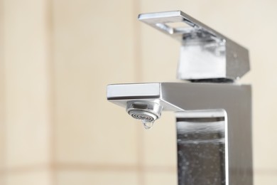 Photo of Water saving concept. Water dripping from tap indoors, closeup. Space for text