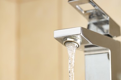 Photo of Water saving concept. Stream of water flowing from tap indoors, low angle view. Space for text