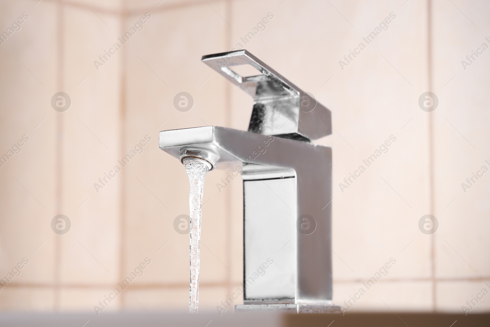 Photo of Water saving concept. Stream of water flowing from tap indoors, closeup