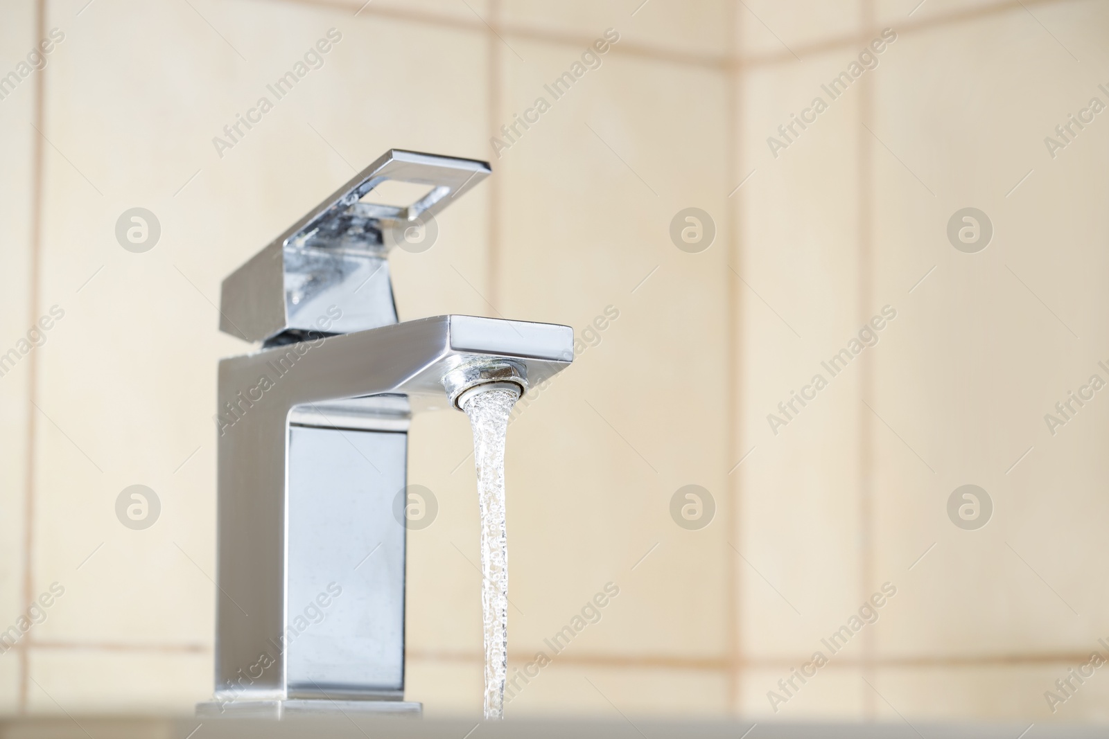 Photo of Water saving concept. Stream of water flowing from tap indoors, closeup. Space for text