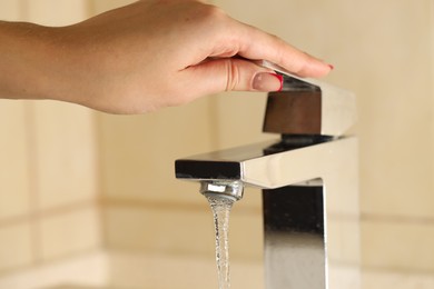 Photo of Water saving concept. Woman turning tap on indoors, closeup