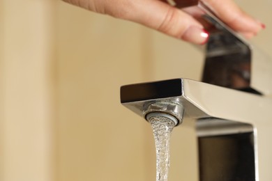Photo of Water saving concept. Woman turning tap on indoors, closeup