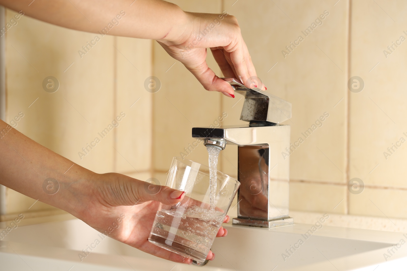 Photo of Water saving concept. Woman filling glass with tap water indoors, closeup