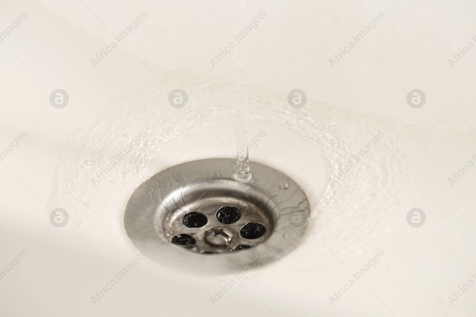 Photo of Water saving concept. Water going into sink drain, closeup