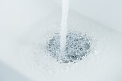 Photo of Water saving concept. Water going into sink drain, closeup