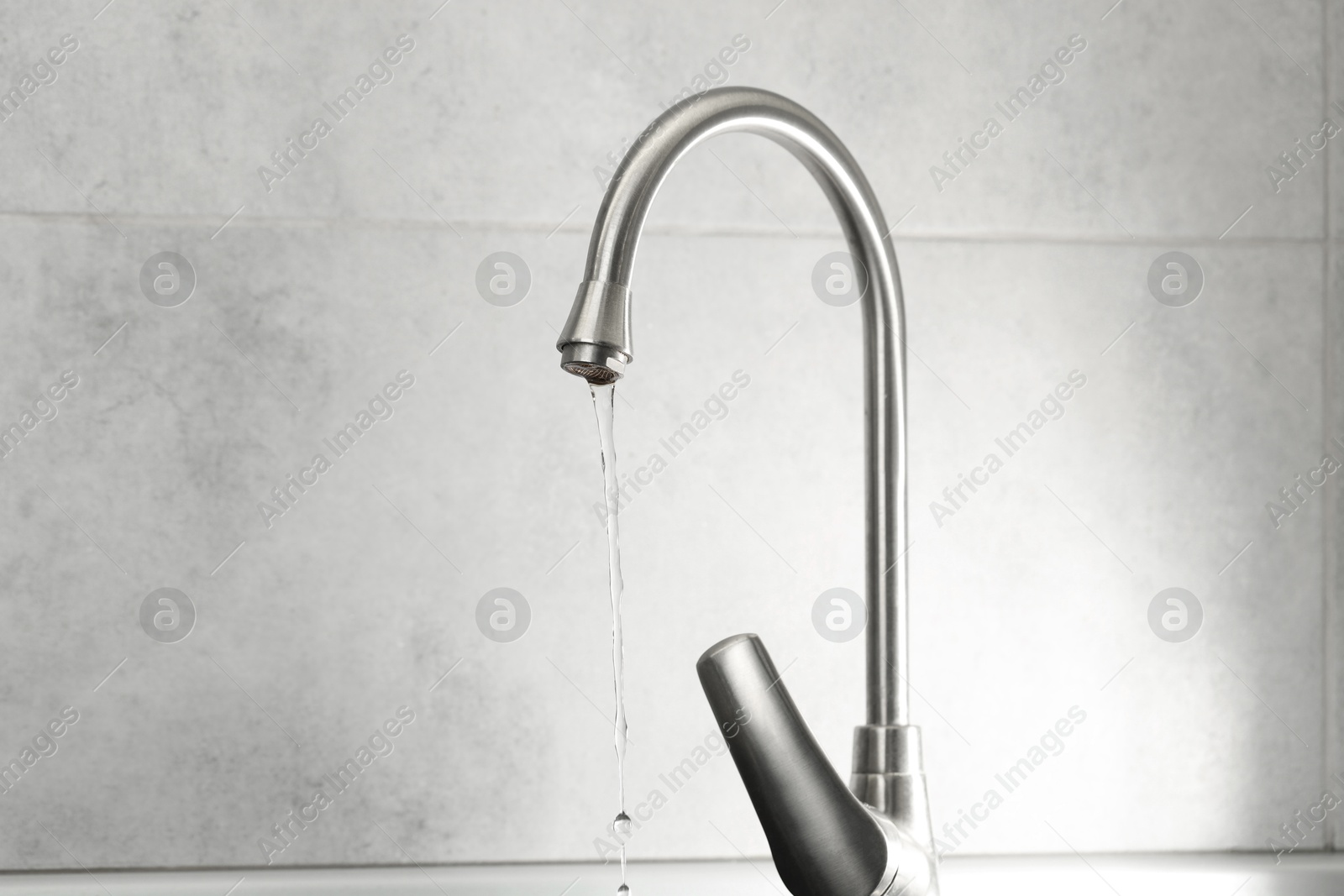 Photo of Water saving concept. Stream of water flowing from tap indoors, closeup. Space for text
