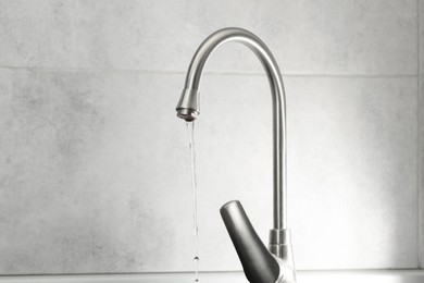 Photo of Water saving concept. Stream of water flowing from tap indoors, closeup. Space for text