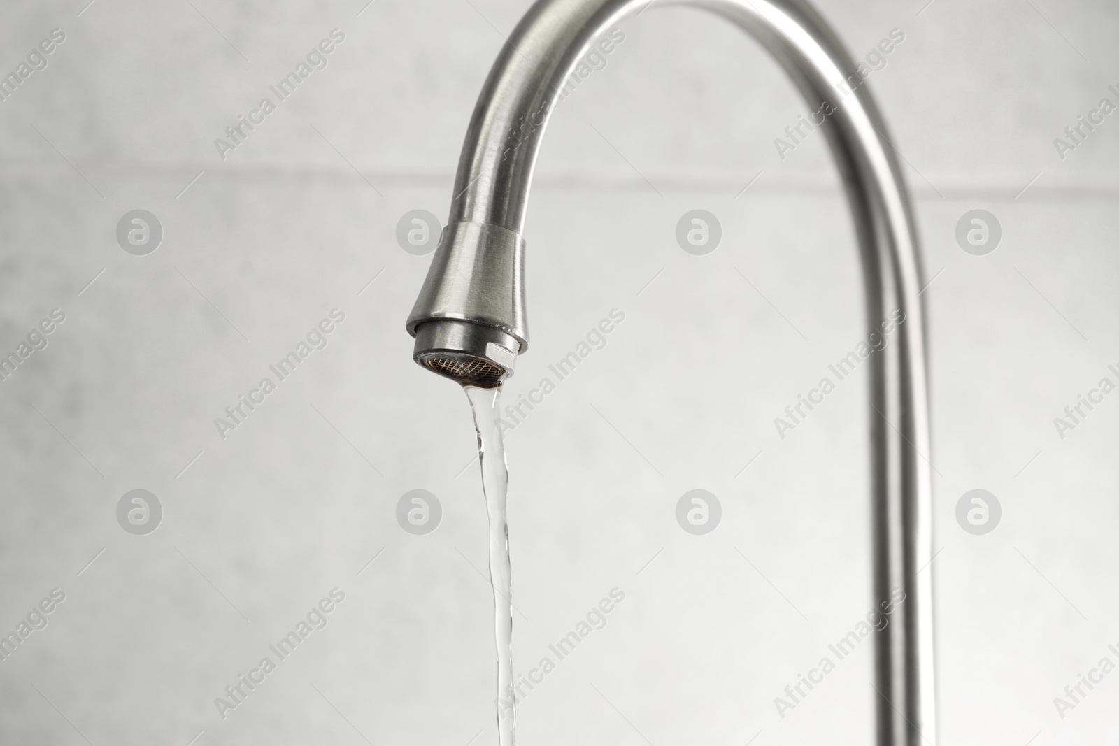 Photo of Water saving concept. Stream of water flowing from tap indoors, closeup