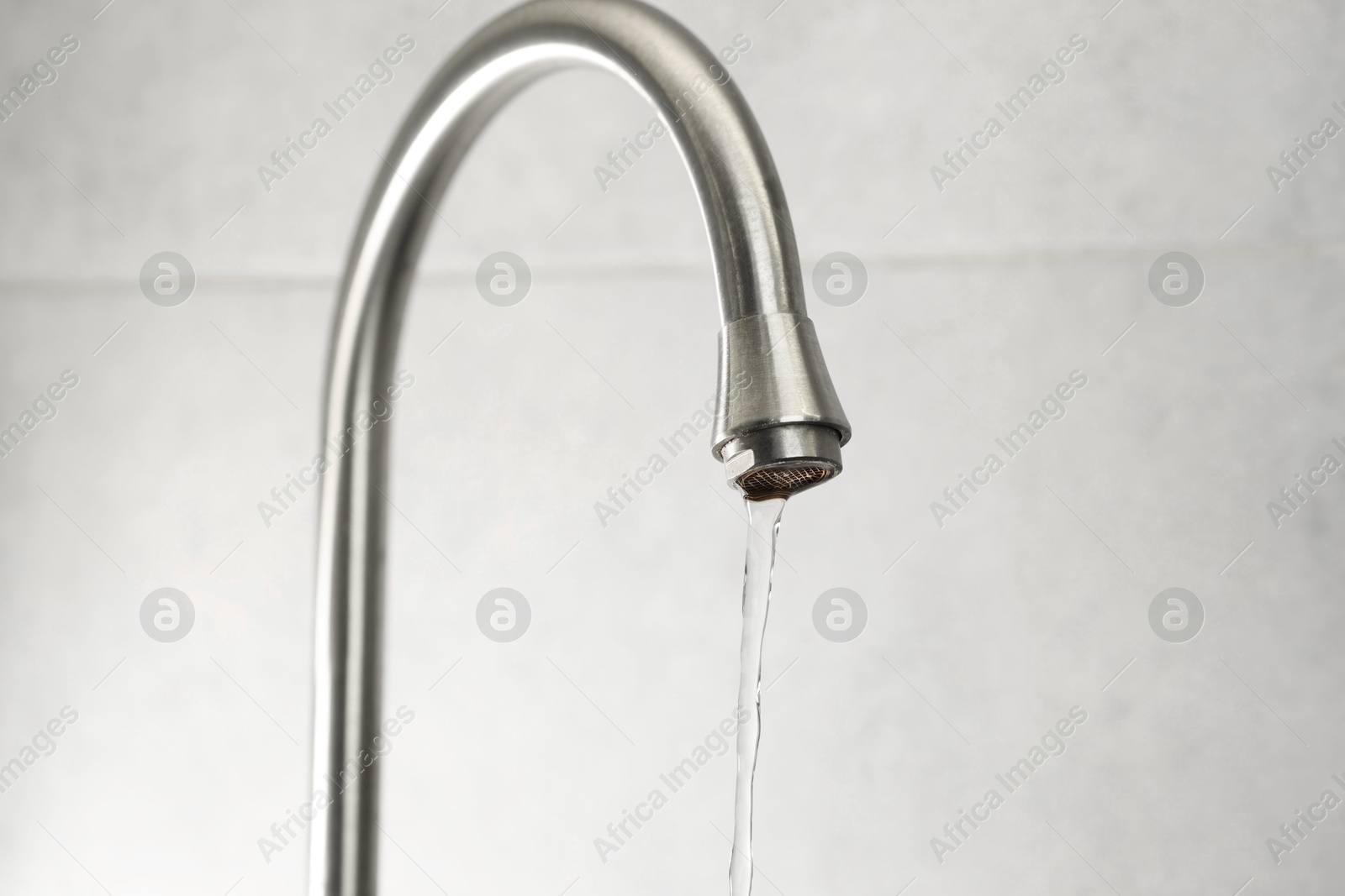 Photo of Water saving concept. Stream of water flowing from tap indoors, closeup