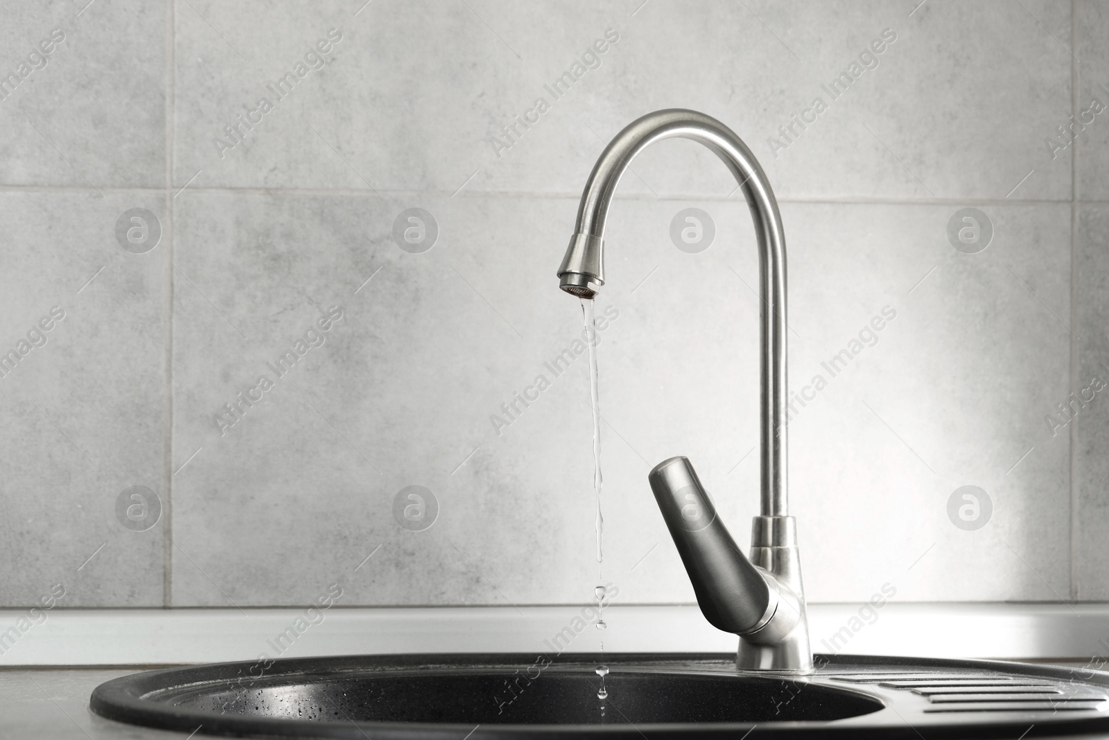 Photo of Water saving concept. Stream of water flowing from tap indoors, closeup. Space for text