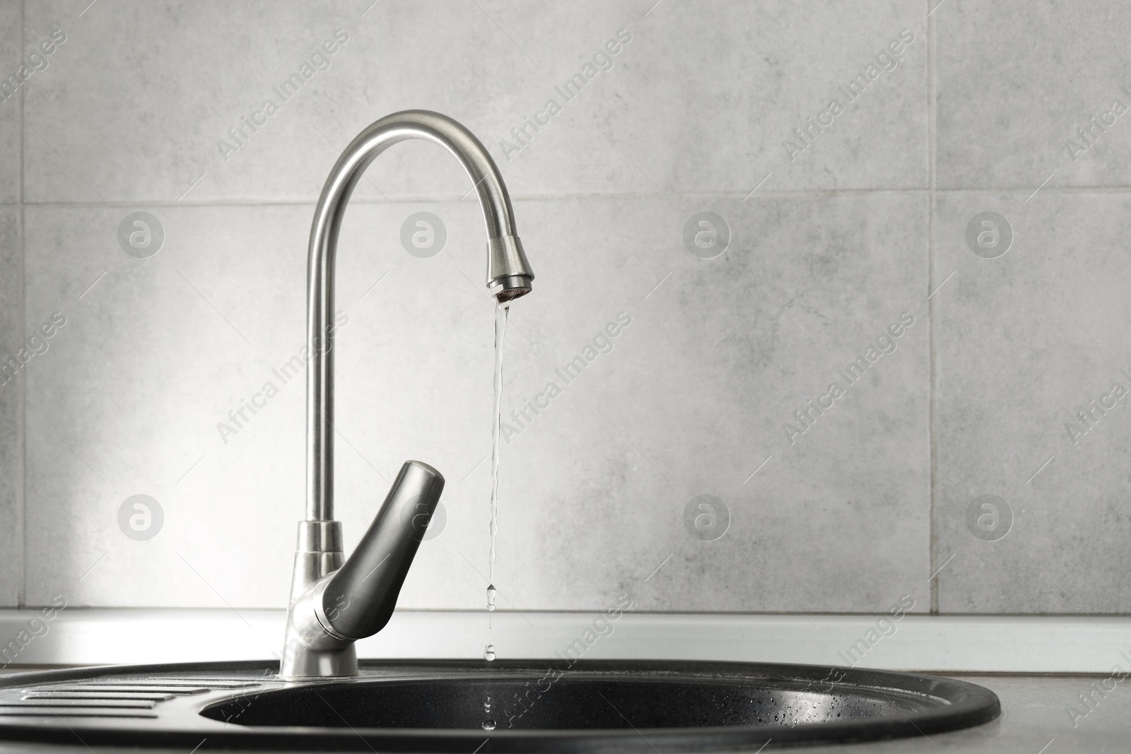 Photo of Water saving concept. Stream of water flowing from tap indoors, closeup. Space for text