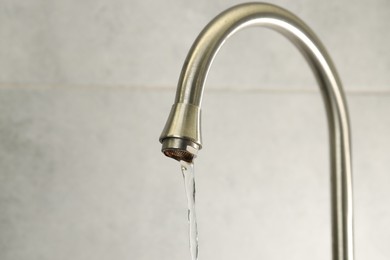 Photo of Water saving concept. Stream of water flowing from tap indoors, closeup