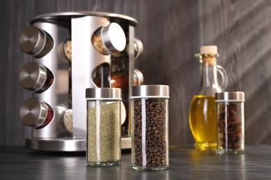 Photo of Different spices in glass jars on grey wooden table, closeup