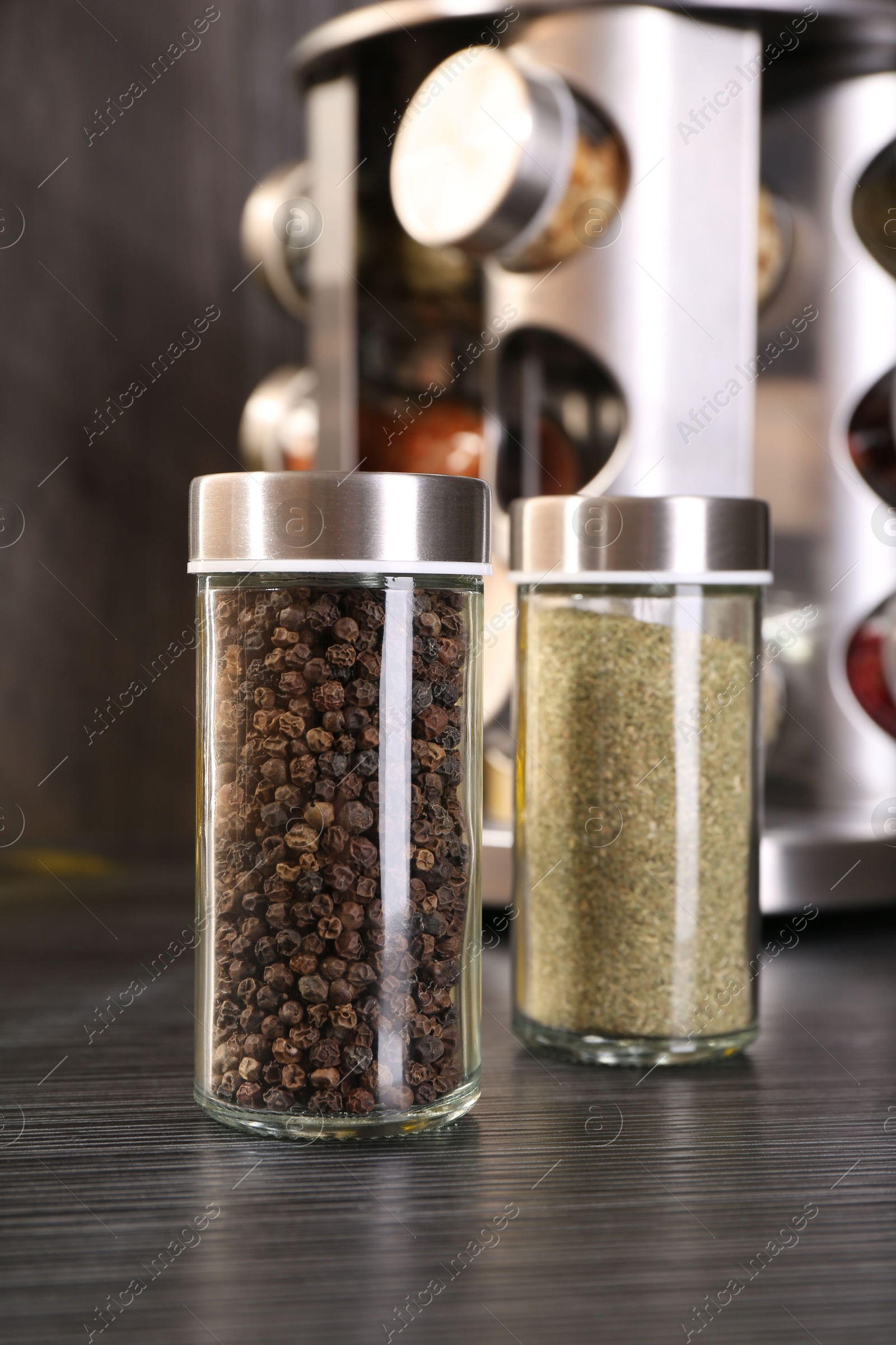 Different spices in glass jars on grey wooden table, closeup Photo of Different spices in glass jars on grey wooden table, closeup