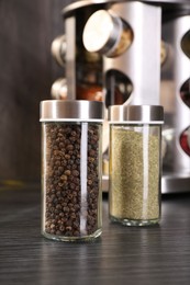 Photo of Different spices in glass jars on grey wooden table, closeup