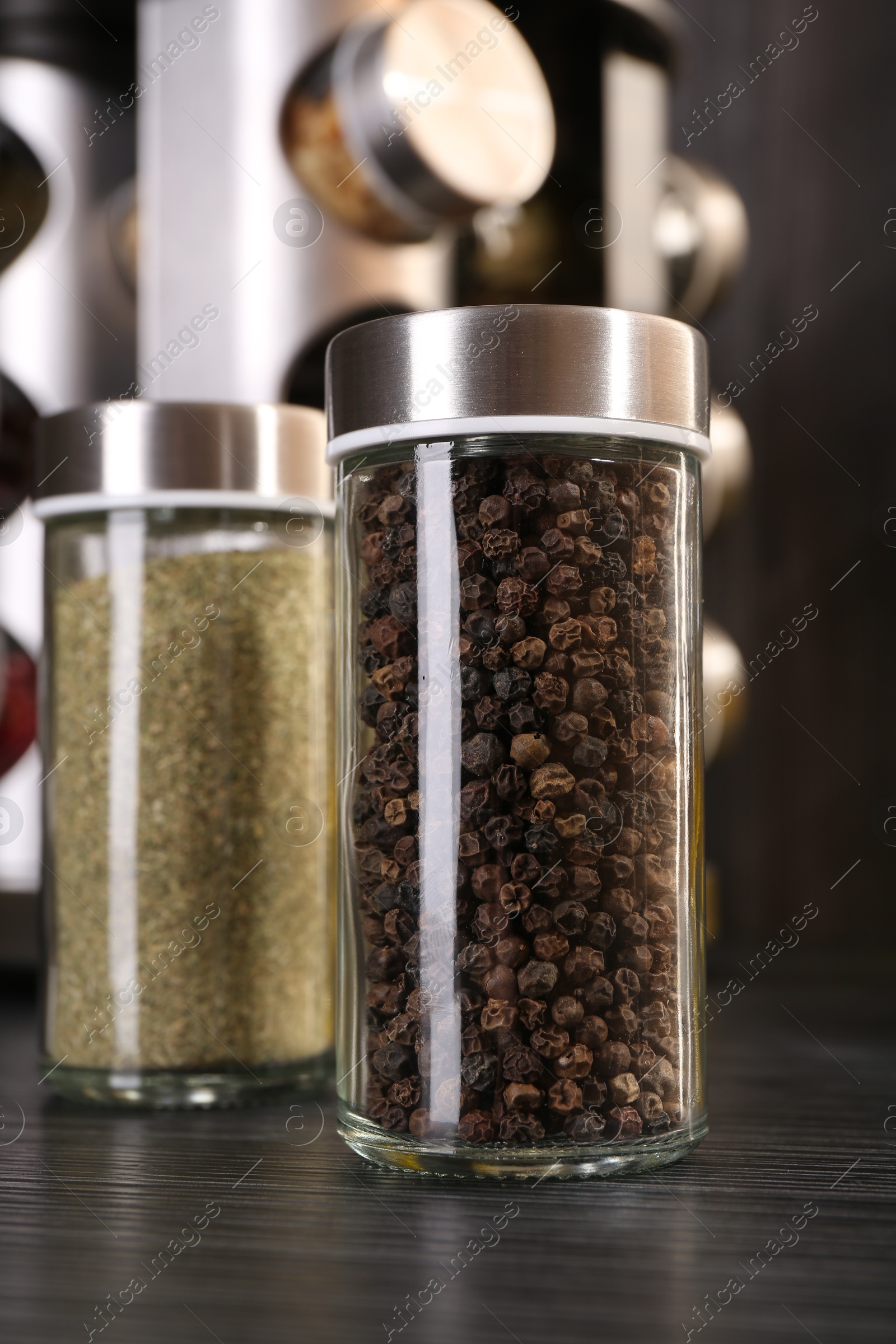 Different spices in glass jars on grey wooden table, closeup Photo of Different spices in glass jars on grey wooden table, closeup