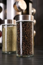 Photo of Different spices in glass jars on grey wooden table, closeup