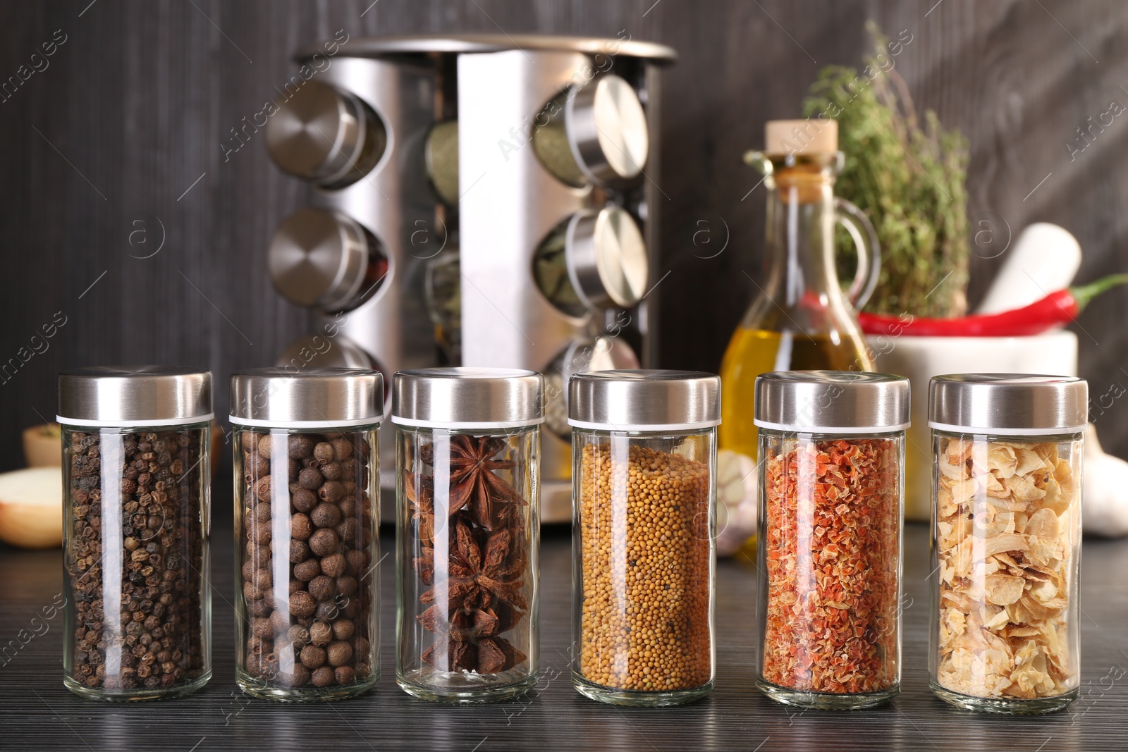 Photo of Different spices in glass jars on grey wooden table