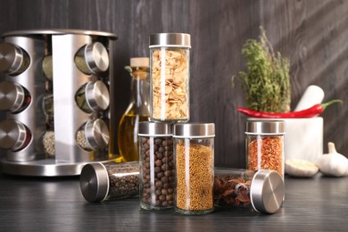 Photo of Different spices in glass jars on grey wooden table