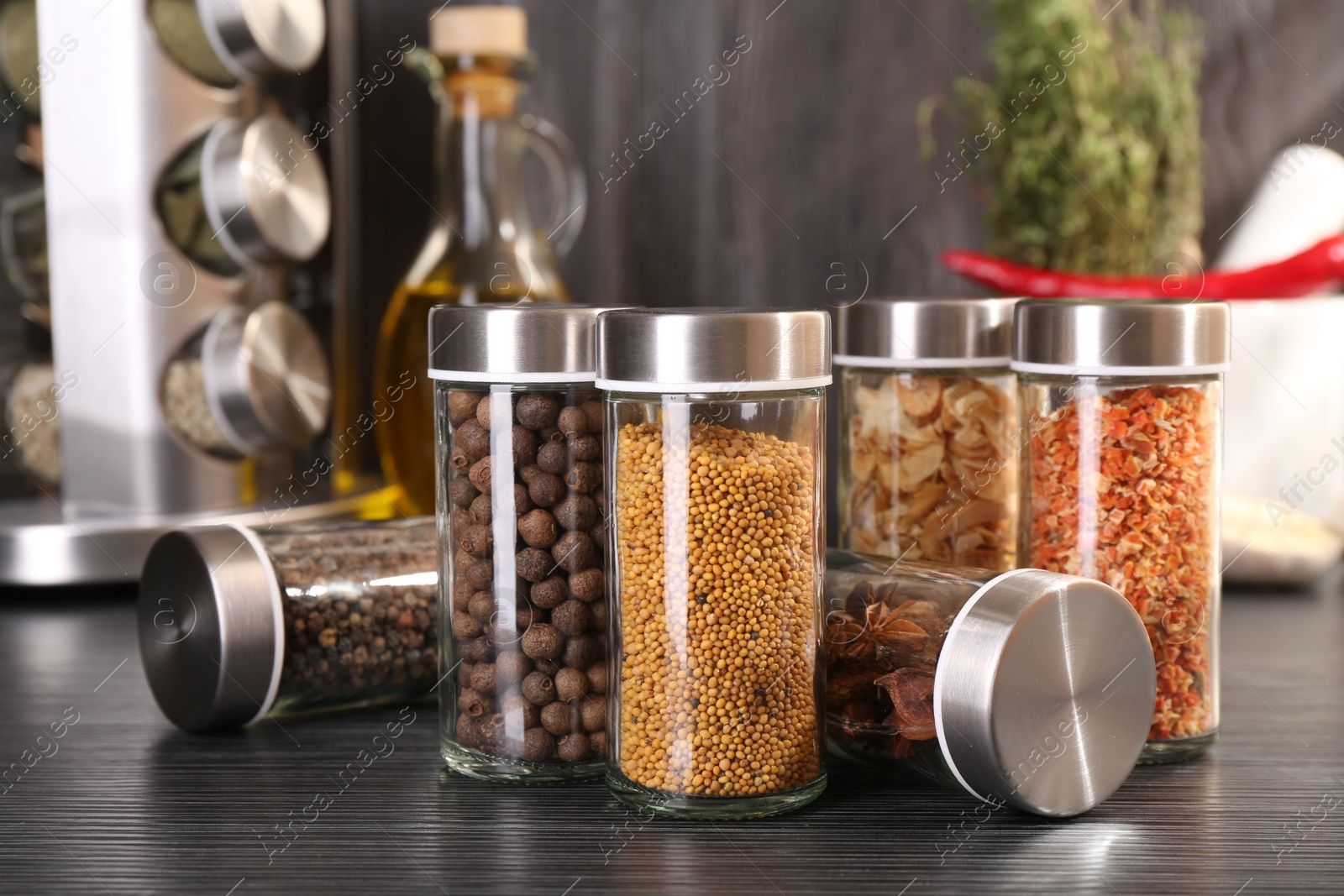 Different spices in glass jars on grey wooden table, closeup Photo of Different spices in glass jars on grey wooden table, closeup