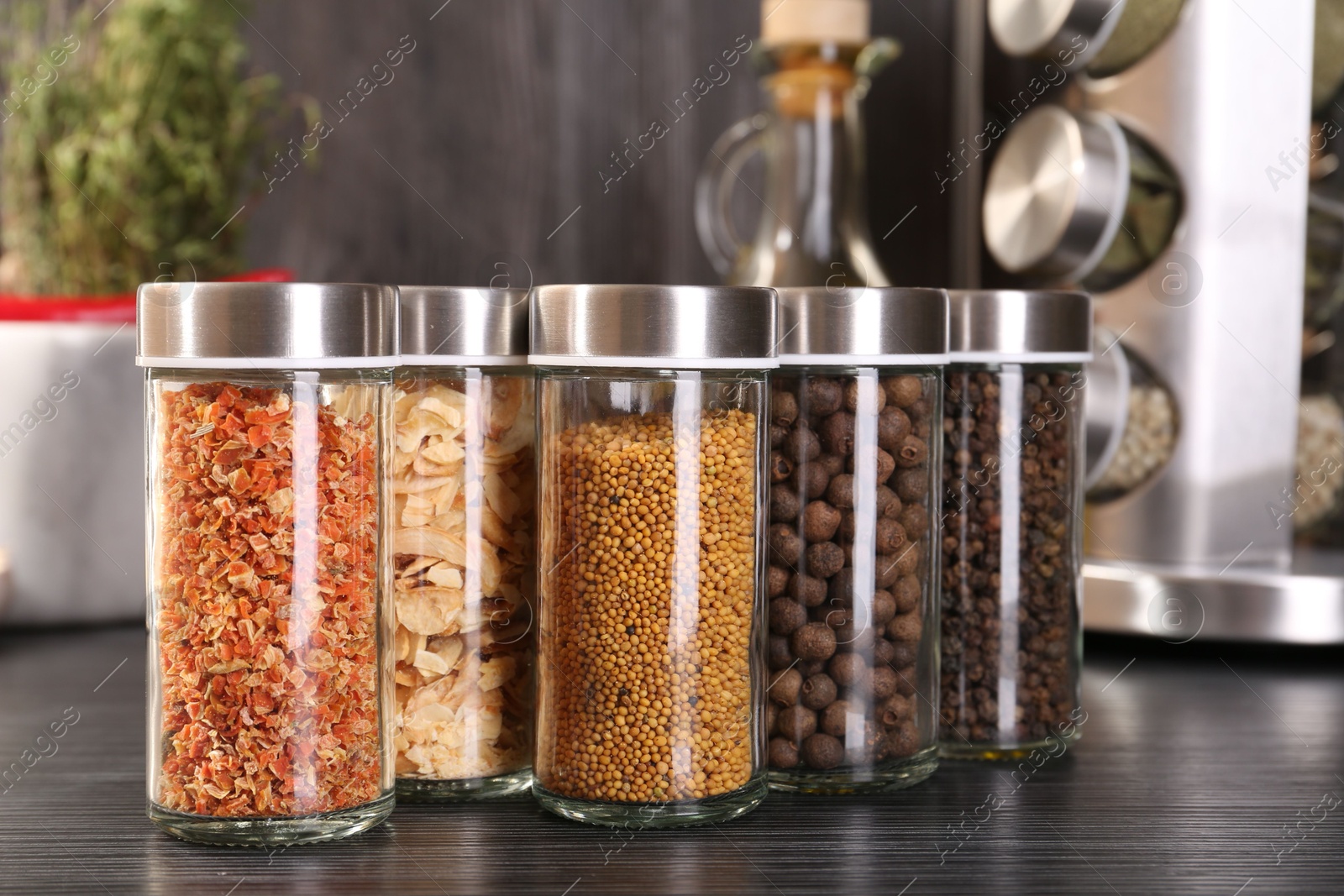 Photo of Different spices in glass jars on grey wooden table, closeup