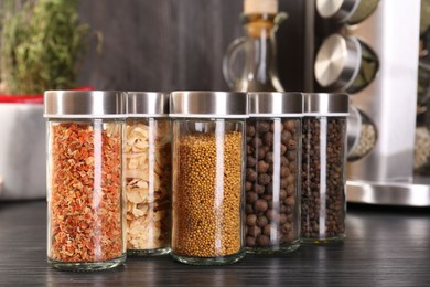 Photo of Different spices in glass jars on grey wooden table, closeup