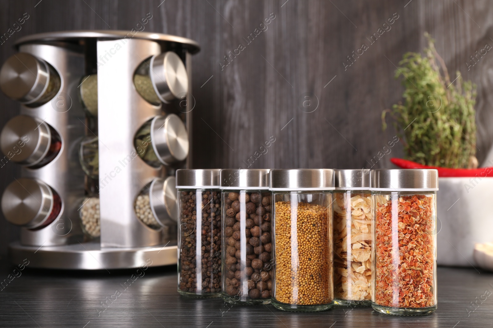 Different spices in glass jars on grey wooden table Photo of Different spices in glass jars on grey wooden table