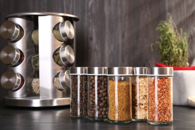 Photo of Different spices in glass jars on grey wooden table